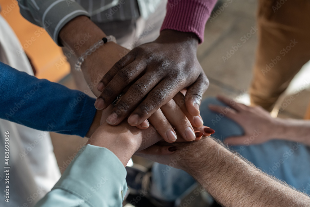 Pile of hands of multi-ethnic group of contemporary employees symbolizing partnership, business union, team building and company spirit Pile of hands of multi-ethnic group of contemporary employees symbolizing partnership, business union, team building and company spirit