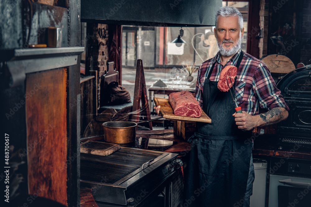 Gray haired butcher and his job in old fashioned meat shop Gray haired butcher and his job in old fashioned meat shop