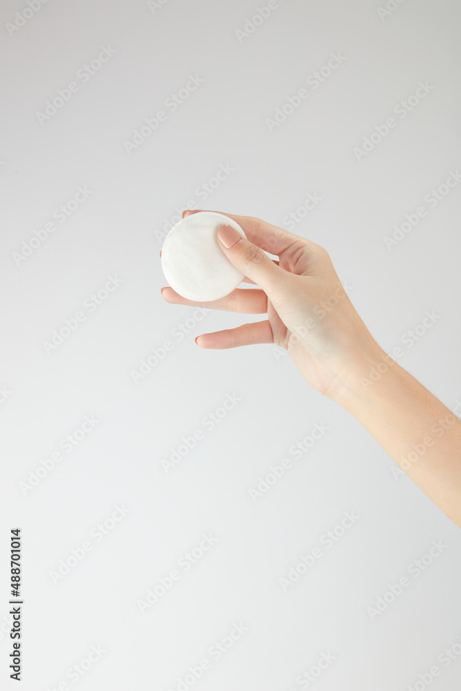 Hand model holding a white cotton pad with a white background for cosmetic advertising