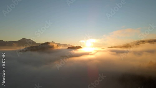 Normal drone footage in Bled Slovenia captured at sunrise with in the nature with beautiful mountains and landscapes cover in fog and nice golden hour colors filmed in  dynamic movement from above photo