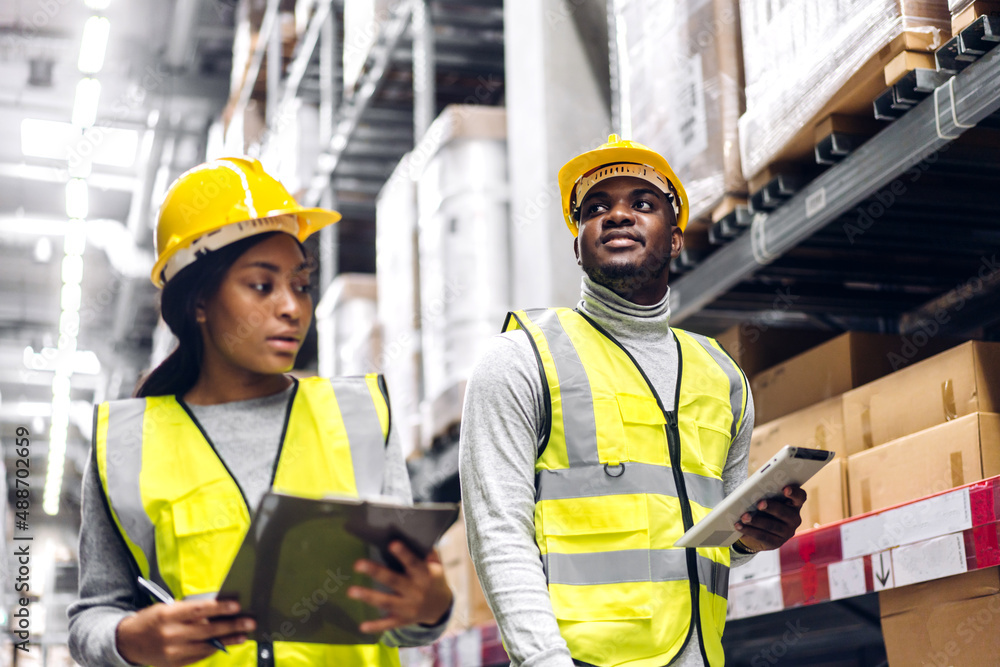 Portrait two african american engineer team shipping order detail on tablet check goods and supplies on shelves with goods inventory in factory warehouse.logistic industry and business export Portrait two african american engineer team shipping order detail on tablet check goods and supplies on shelves with goods inventory in factory warehouse.logistic industry and business export
