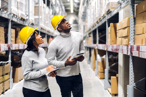 Portrait two african american engineer team shipping order detail on tablet check goods and supplies on shelves with goods inventory in factory warehouse.logistic industry and business export