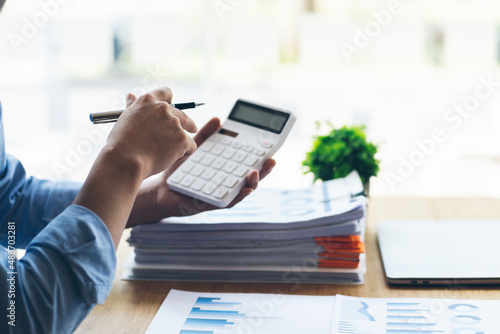 A financial businessman, a young man analyzes financial data using a computer and calculator to compute and summarize the data in a graph to propose to the president. photo