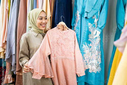 excited asian muslim woman trying new clothes © Odua Images