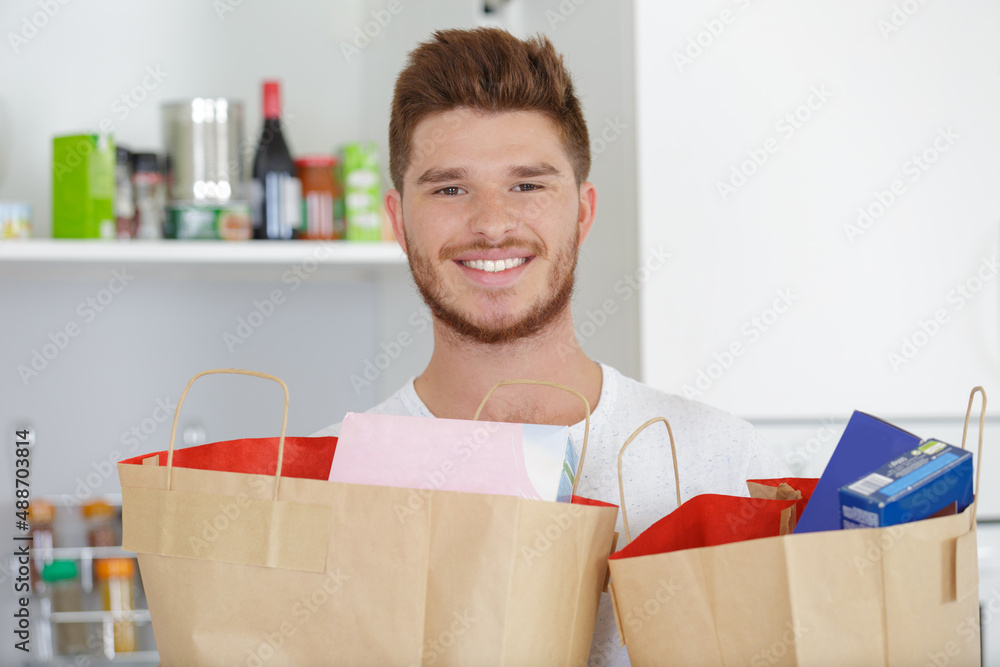 handsome man holding a paper bag full of healthy food handsome man holding a paper bag full of healthy food