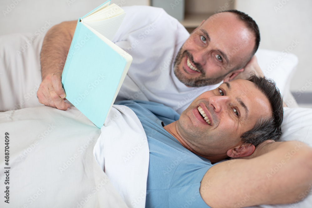 Obraz premium two mature men in bed looking at a book
