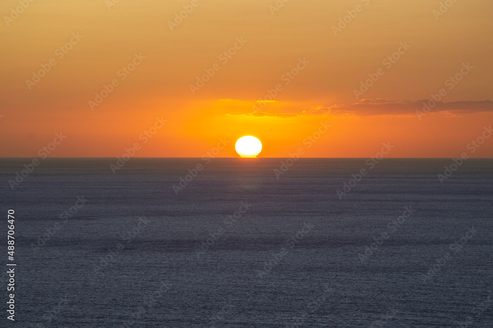 The sun is above the horizon during sunset at sea