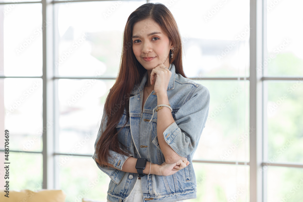 Portrait closeup shot of Asian young beautiful long brown hair female teenager fashion model in casual blue street denim jeans jacket standing smiling look at camera holding hand at chin crossed arm Portrait closeup shot of Asian young beautiful long brown hair female teenager fashion model in casual blue street denim jeans jacket standing smiling look at camera holding hand at chin crossed arm