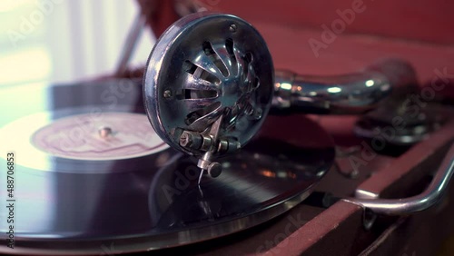head of a gramophone with a metal needle slides on a vinyl record. close-up, selective focus. old vintage phonograph.