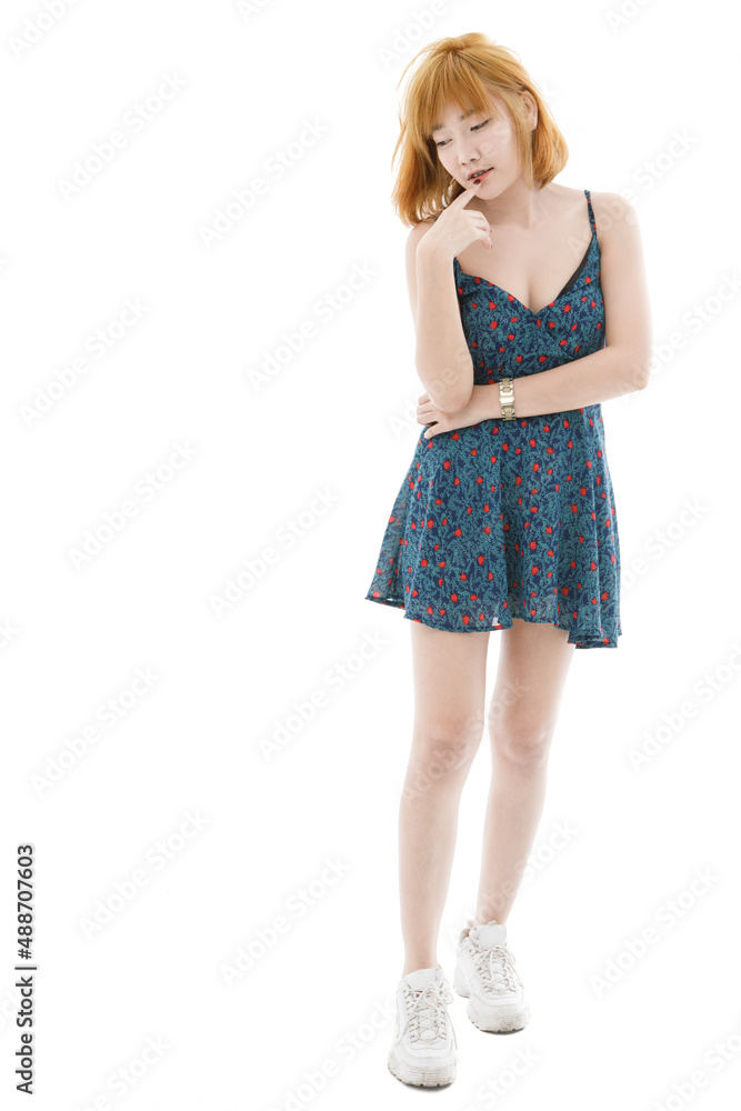 Naklejka premium Isolated cutout studio full body shot of Asian young sexy blonde short hair female fashion model in camisole dress and sneakers standing holding hand touching lips crossed arm on white background