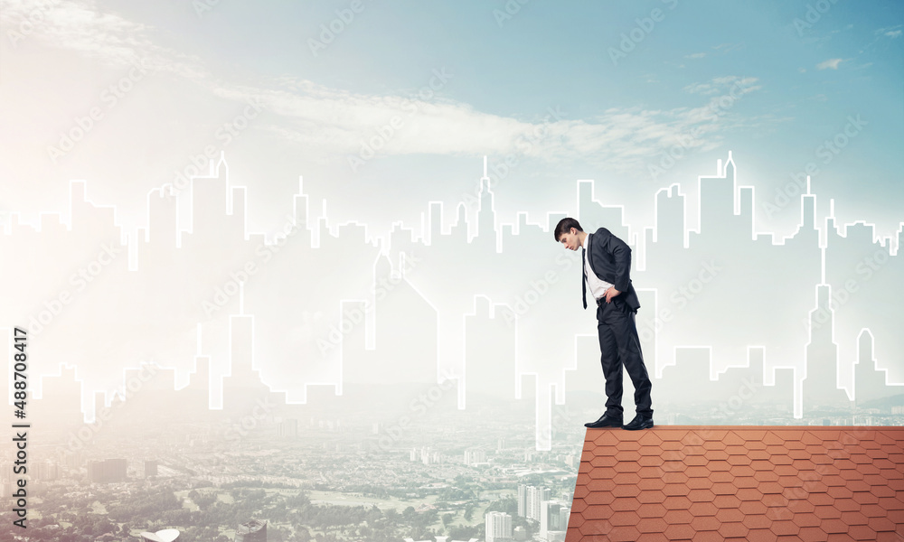 Businessman looking down from roof and modern cityscape at backg Businessman looking down from roof and modern cityscape at backg