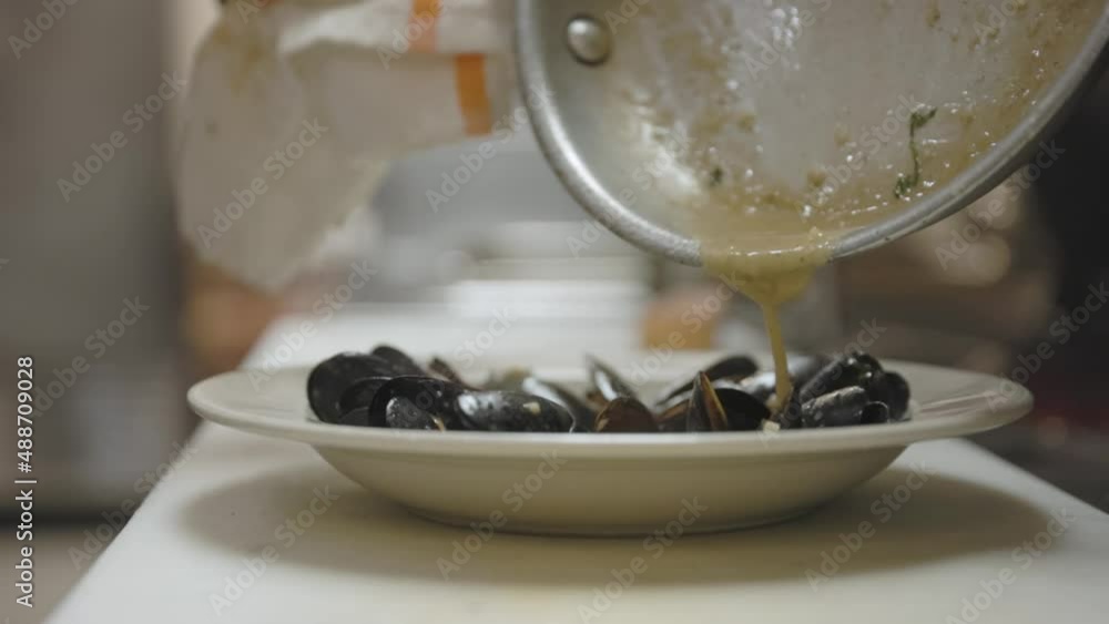 Chef Drizzling Sauce onto Mussels in a Kitchen Chef Drizzling Sauce onto Mussels in a Kitchen