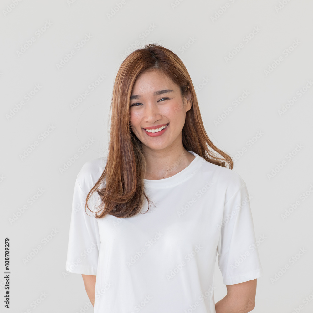 Portrait isolated cutout studio shot of Asian young happy cheerful long brown hair female teenager model in casual shirt standing smiling look at camera holding hand on elbow on white background