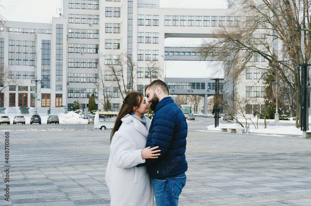 couple walking in city. Young business man in a blue jacket with a beard. And a cute woman in long coat. Family holiday and togetherness, date. Urban