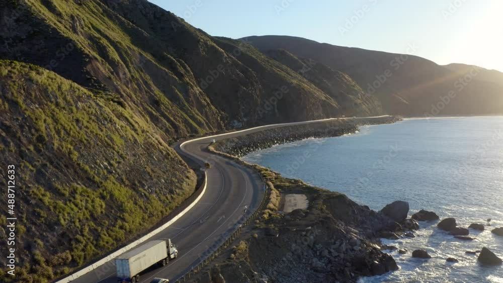 On the open road, ready for a road trip. Aerial view of a road running between a mountain and the ocean. Top view of a coastline road and beach resorts at sunset. Malibu Beach coastline in California On the open road, ready for a road trip. Aerial view of a road running between a mountain and the ocean. Top view of a coastline road and beach resorts at sunset. Malibu Beach coastline in California