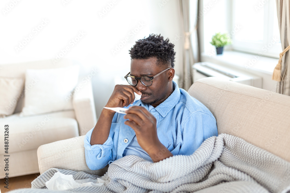 Sickness, seasonal virus problem concept. Man being sick having flu lying on bed looking at temperature on thermometer. Sick man lying in bed with high fever. Cold flu coronavirus, covid19 Sickness, seasonal virus problem concept. Man being sick having flu lying on bed looking at temperature on thermometer. Sick man lying in bed with high fever. Cold flu coronavirus, covid19
