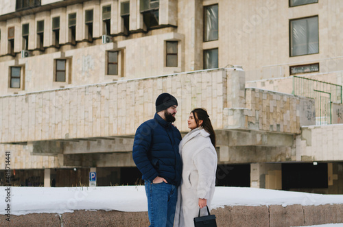 Love story of couple walking in city. Young business man in a blue jacket with a beard. And a cute woman in long coat. Family holiday and togetherness, date. Urban.