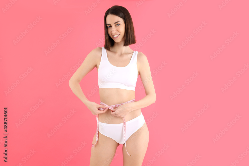 Concept of weight loss with young slim woman on pink background Concept of weight loss with young slim woman on pink background