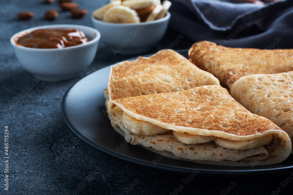 Pancakes with chocolate banana filling. Delicious breakfast of pancakes envelopes on a plate, dark concrete background. Pancakes with chocolate banana filling. Delicious breakfast of pancakes envelopes on a plate, dark concrete background.