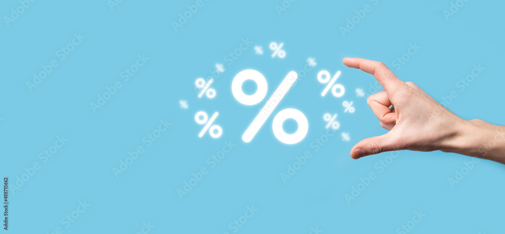 Male hand holding interest rate percent icon on blue background. Interest rate financial and mortgage rates concept.Banner with copy space Male hand holding interest rate percent icon on blue background. Interest rate financial and mortgage rates concept.Banner with copy space