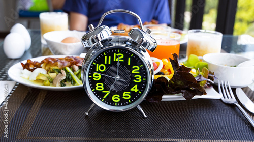 Selective focus of alarm clock for a Healthy food of salad Intermittent fasting concept. Time to lose weight , eating control or time to diet concept.