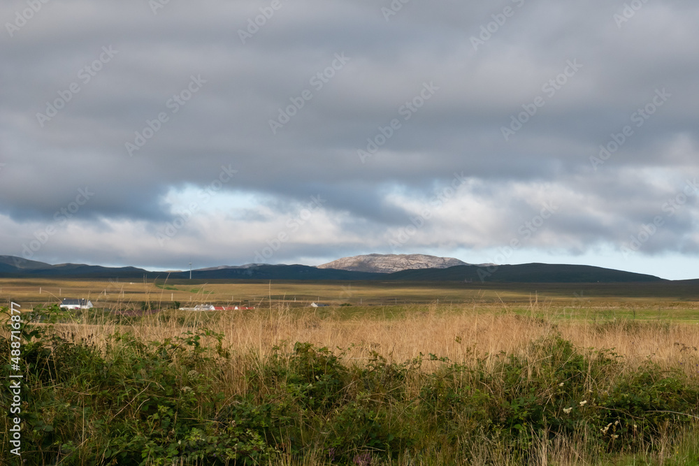 Dramatic clouds over an illuminated rocky hill in the inland landscape of the Isle of Islay, summer afternoon in the Inner Hebrides