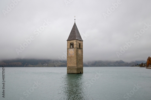 The Steeple of the old Church in the submerged Village of Curon, rising above the surface of Lake Reschen (in Curon Venosta, Italy)  photo