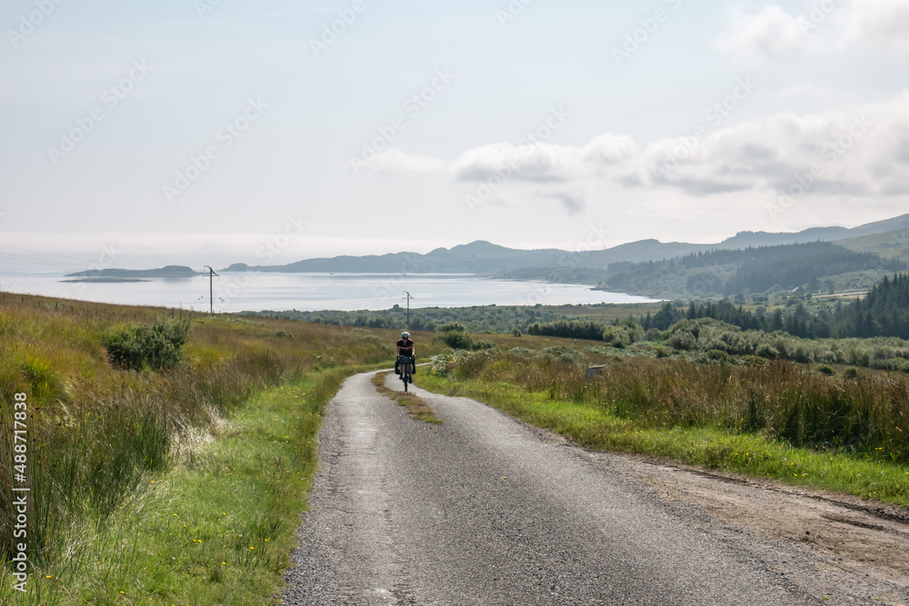lonely cyclist cycling on up a road on the Isle of Jura on a beautiful simmer day lonely cyclist cycling on up a road on the Isle of Jura on a beautiful simmer day