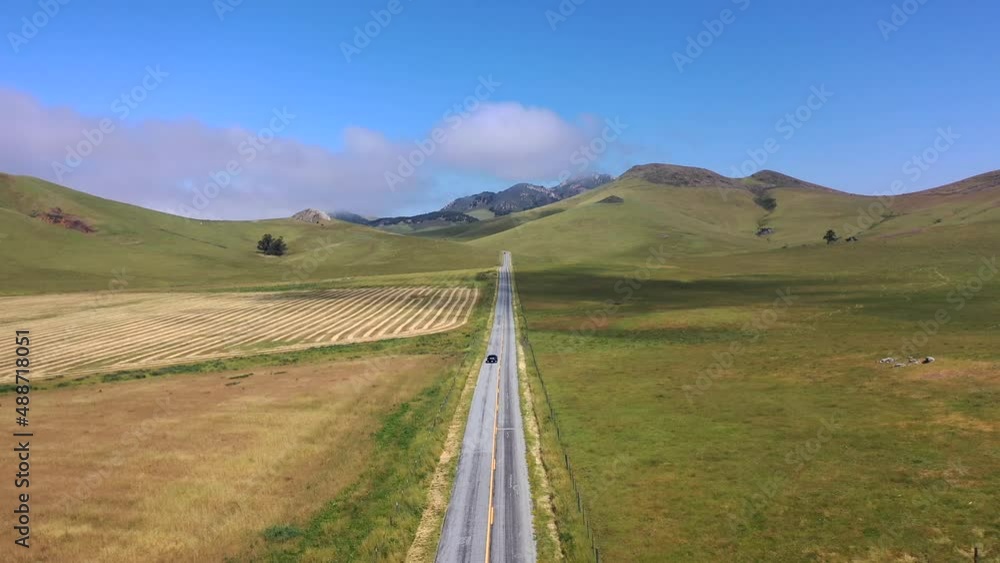Car Driving Through Empty Road Between Grassy Fields At Daytime In San Luis Obispo, California. - aerial Car Driving Through Empty Road Between Grassy Fields At Daytime In San Luis Obispo, California. - aerial