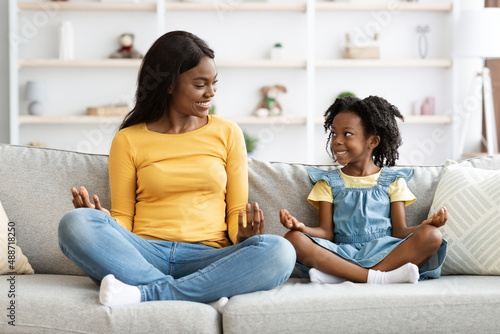 Family Hobbies. Happy Black Mom And Little Daughter Meditating Together At Home