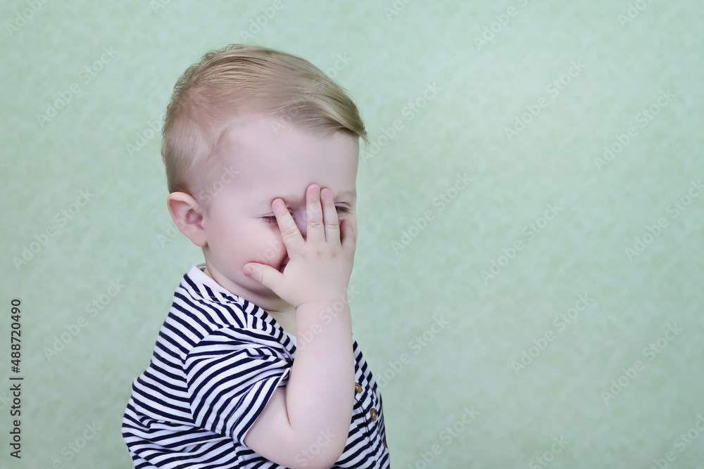 Defocused funny, happy child smiles and covers his face with his hand. The little child is embarrassed. Copy space - people concept, children's advertising, fun, shame, emotions Defocused funny, happy child smiles and covers his face with his hand. The little child is embarrassed. Copy space - people concept, children's advertising, fun, shame, emotions
