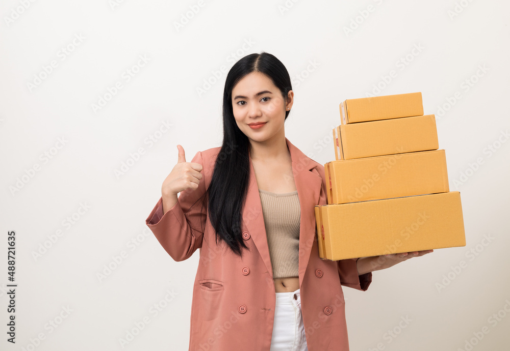 Young beautiful asian woman with many parcel cardboard standing on isolated white background. Delivery woman holding lot of parcel box sending to messenger.