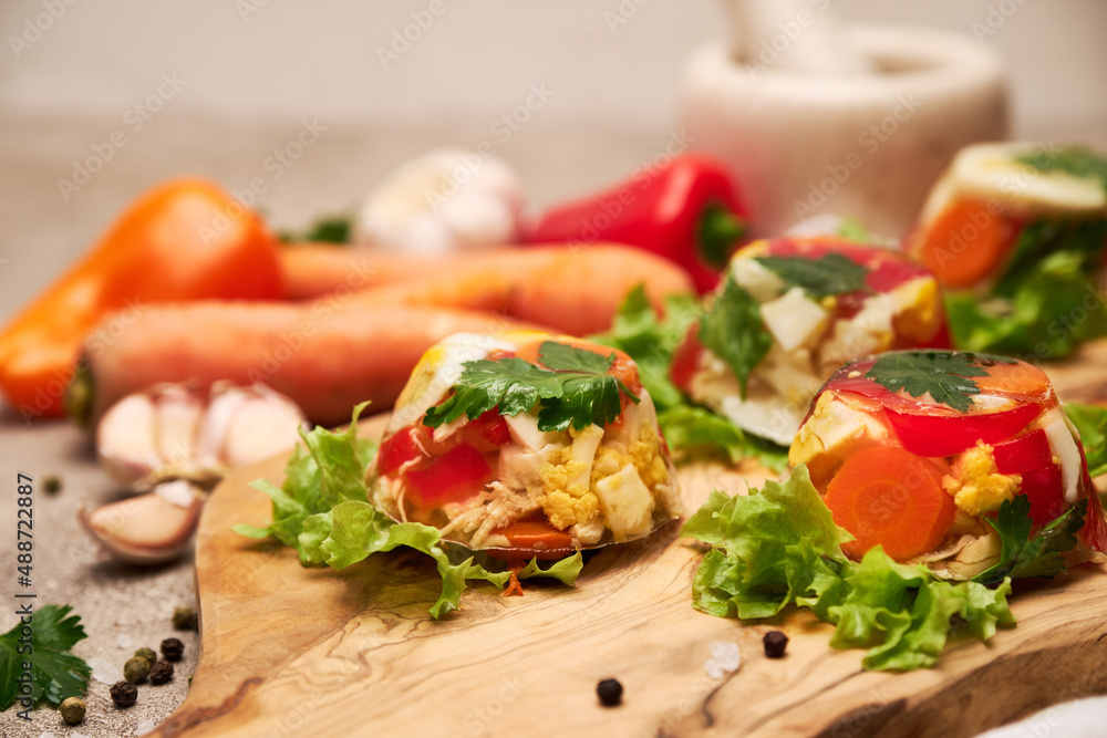 Portion of delicious chicken aspic on serving board on concrete table Portion of delicious chicken aspic on serving board on concrete table