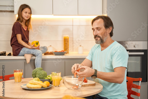 Adult man with daughter preparing salad in the kitchen