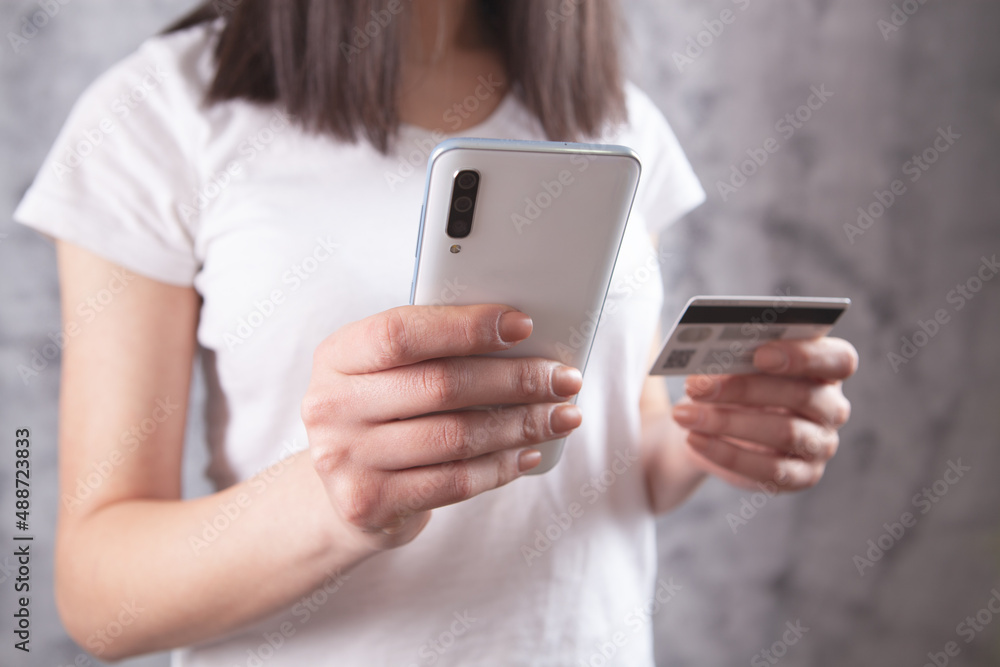 girl holding a phone and a bank card in her hands