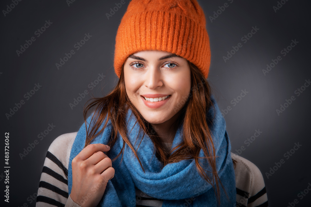Studio shot of beautiful woman wearing knitted hat and scarf while standing at isolated background Studio shot of beautiful woman wearing knitted hat and scarf while standing at isolated background