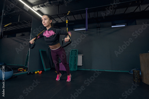 Focused photo on sportswoman doing functional training