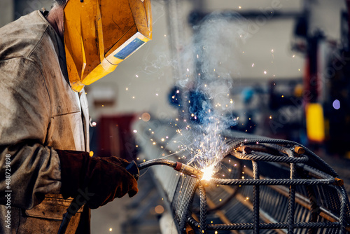 A heavy industry metal worker welding armature in metal factory.