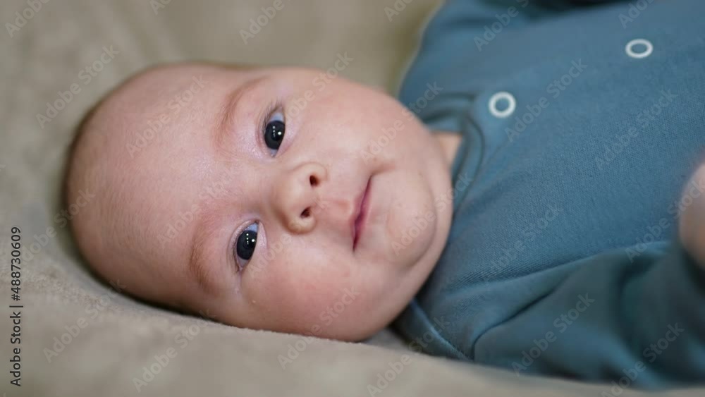 Serene healthy Caucasian child lying on his back. Face portrait of a beautiful peaceful baby staring into camera close up. Serene healthy Caucasian child lying on his back. Face portrait of a beautiful peaceful baby staring into camera close up.