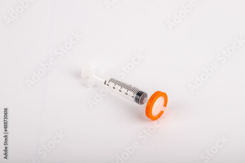 syringe standing on white background with needle tip filter attached.