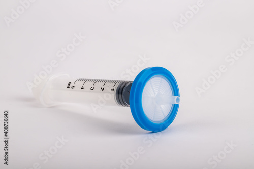 syringe standing on white background with needle tip filter attached.