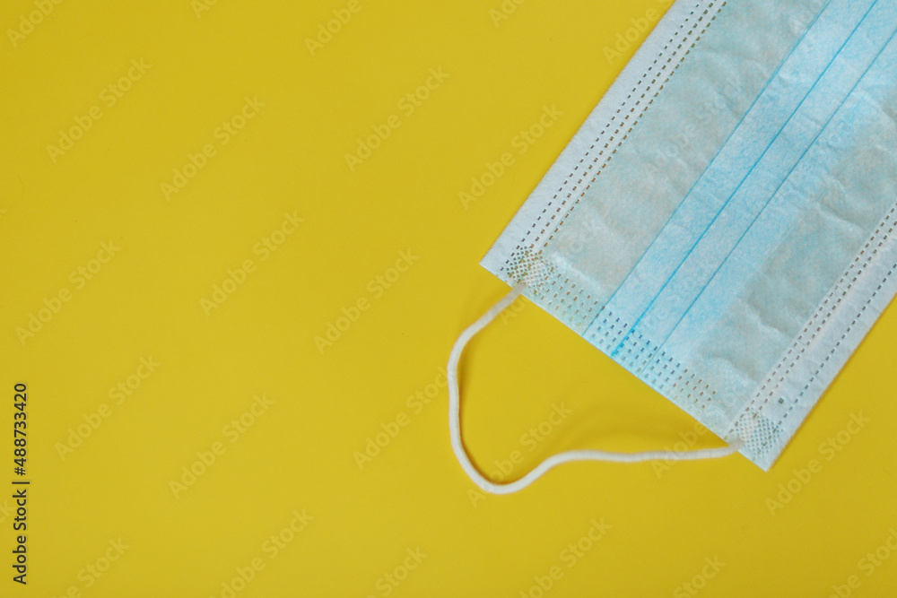 Medical mask on a yellow background in the upper right corner Medical mask on a yellow background in the upper right corner