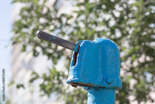 A blue street water pump in a modern city against the backdrop of a nine-story Soviet building
