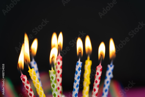 Many burning colorful birthday candles, black background with copy space
