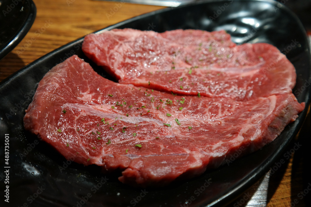 Red raw meat is served on a black plate. Red raw meat is served on a black plate.