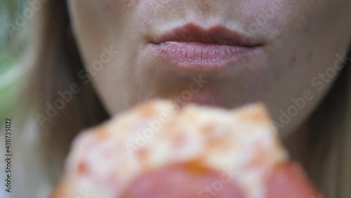 Young woman outdoors eating italian pizza. Close up bites a piece of pizza