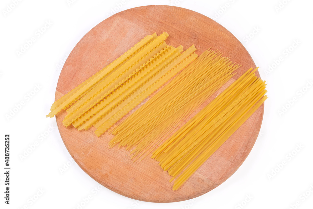 Uncooked long pasta different varieties on a round wooden board Uncooked long pasta different varieties on a round wooden board