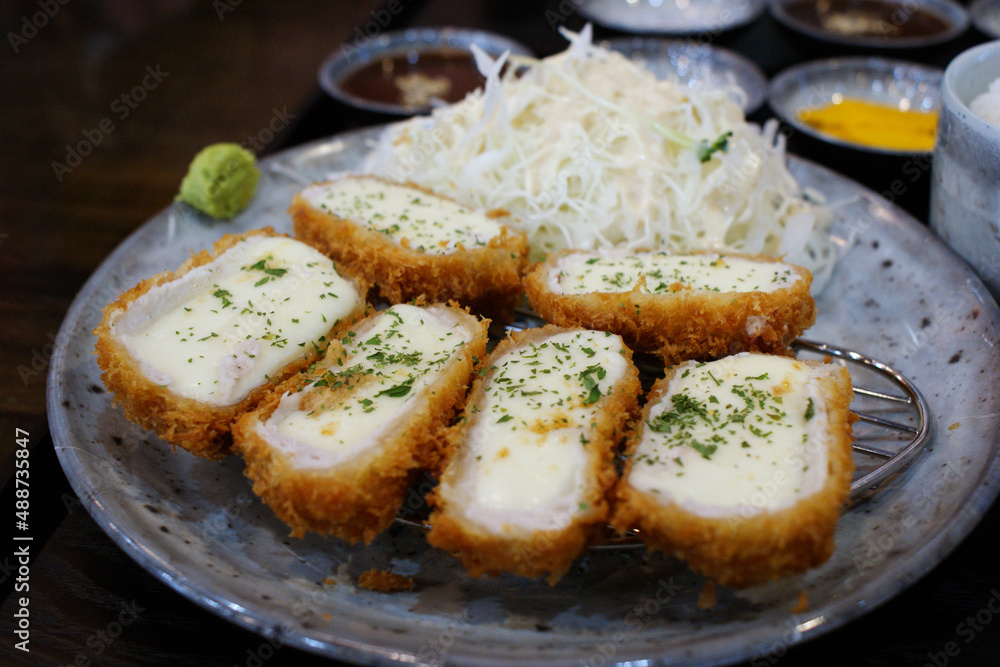 Cheese pork cutlet filled with cheese is served on a round plate.