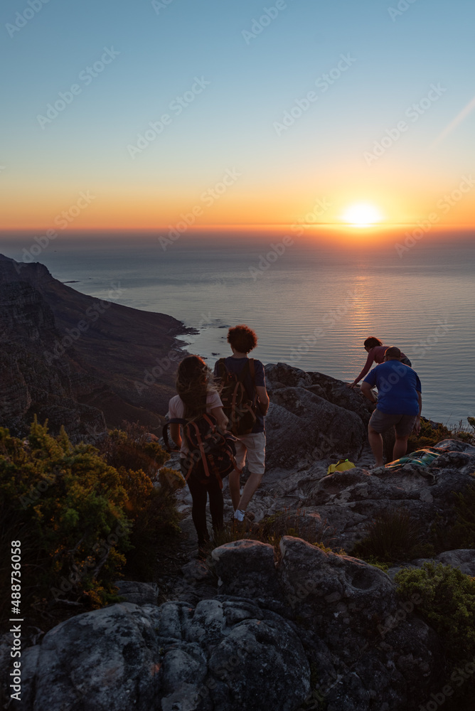 Couple hiking on mountain while the sun is setting. Hiking couple on a mountain enjoying sunset and the view of the sea at sunset. Couple hiking on mountain while the sun is setting. Hiking couple on a mountain enjoying sunset and the view of the sea at sunset.