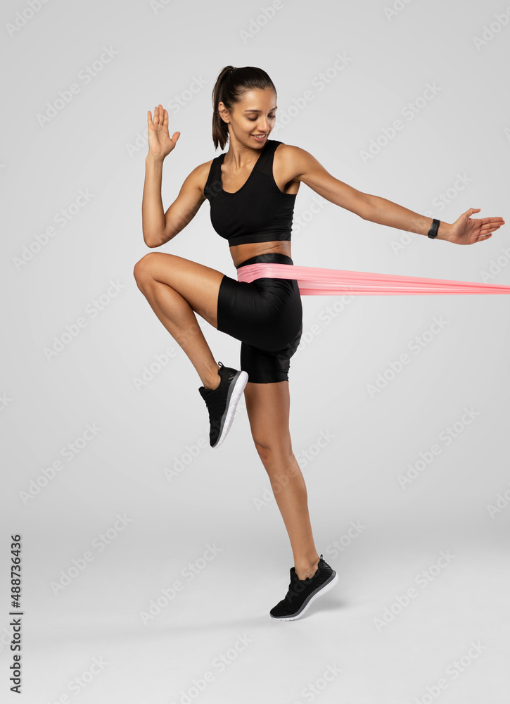 Sportswoman exercising with resistance band. Female with working out with elastic band on white background